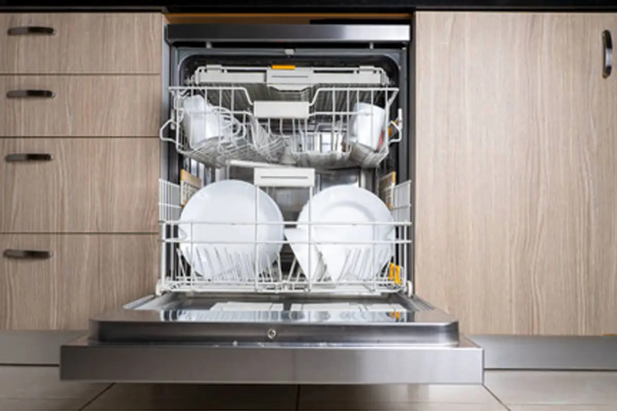Open built-in dishwasher with clean white plates on the lower rack