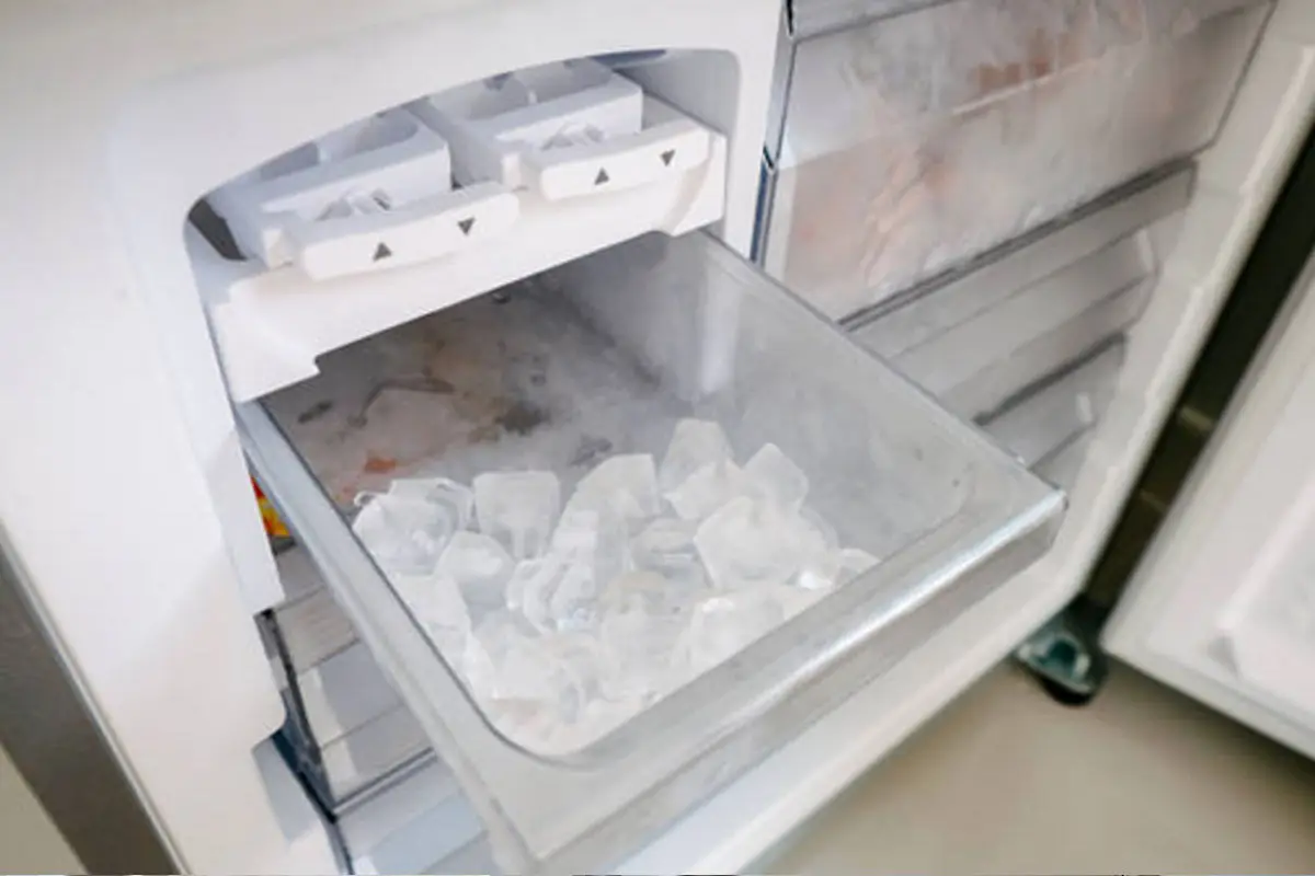 Ice maker bin full of ice cubes inside a refrigerator freezer