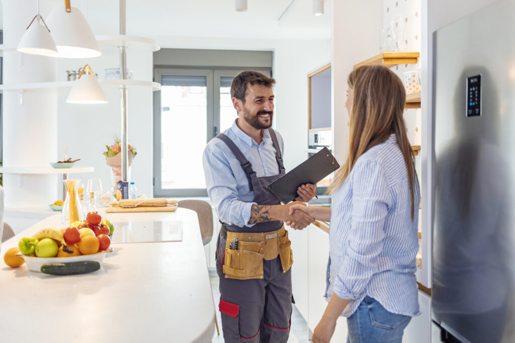 Appliance repair technician shaking hands with a customer in her kitchen