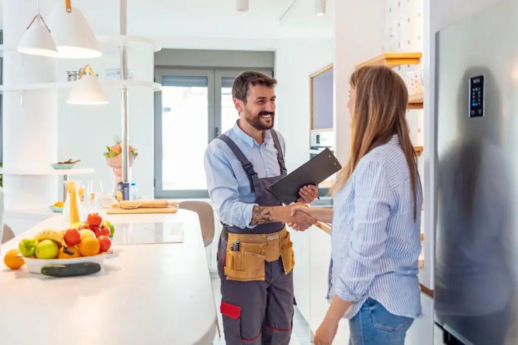 Appliance repair technician shaking hands with a customer in her kitchen