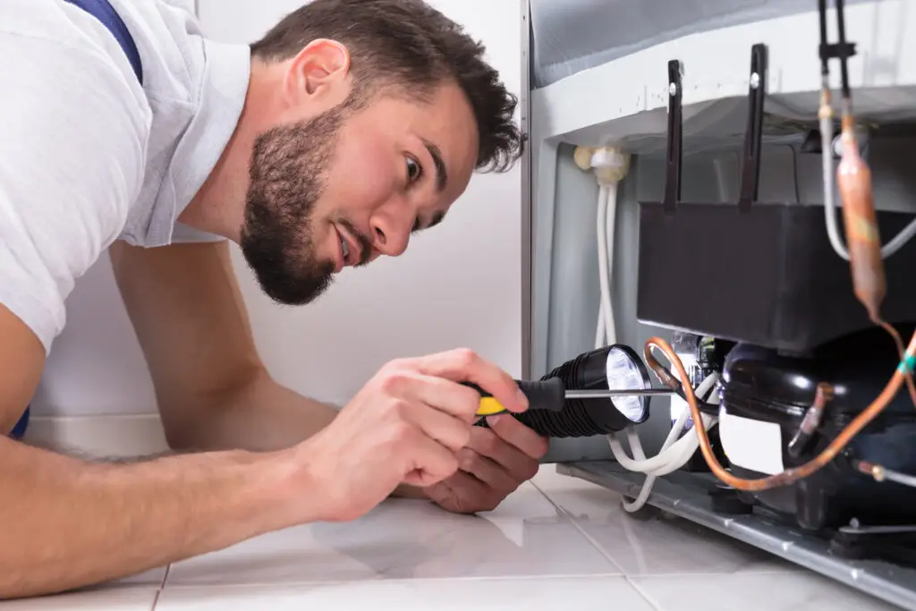 Technician repairing a refrigerator compressor